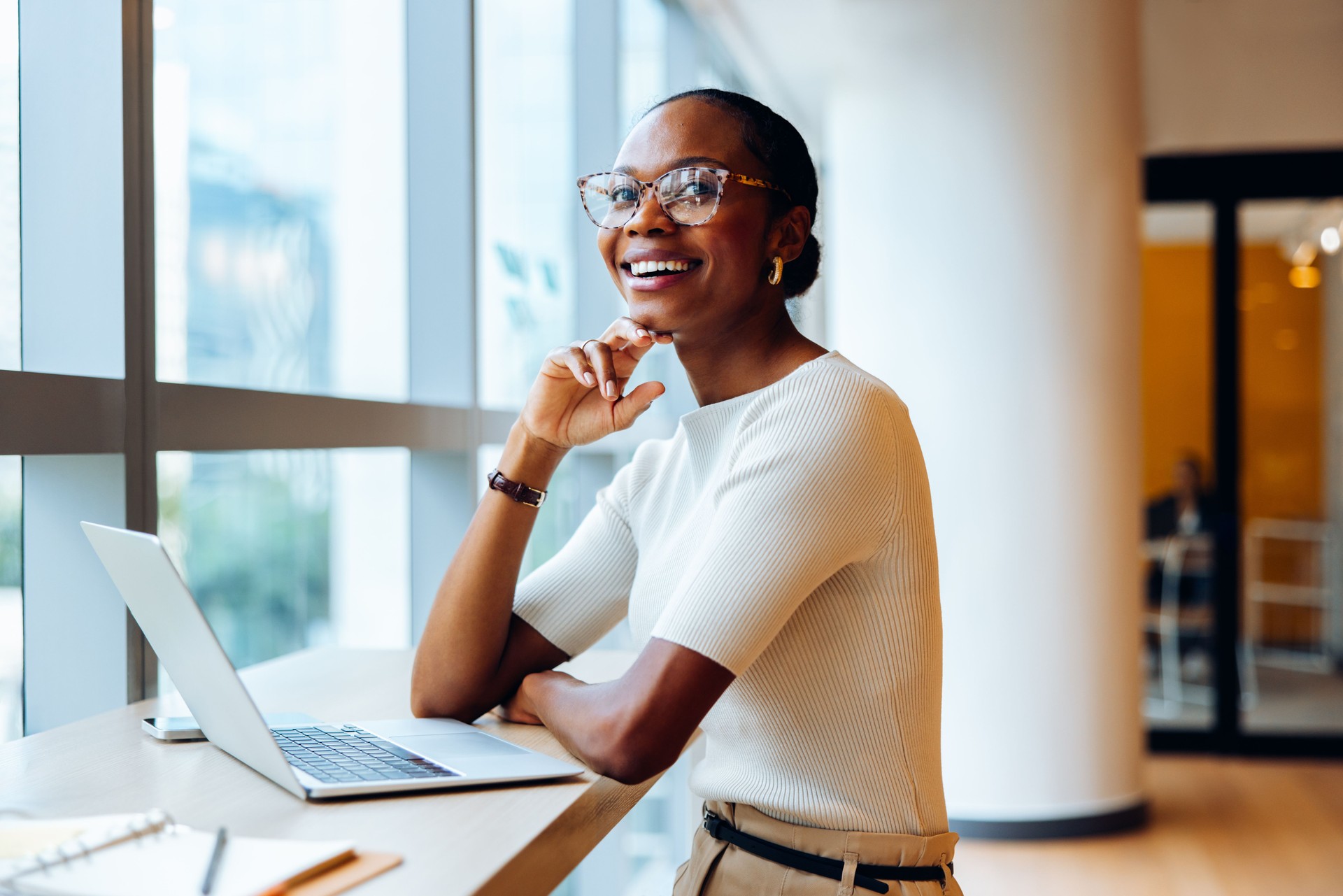 Smiling professional seated at a desk with a laptop in an office